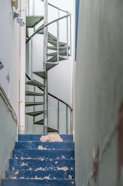 A three-story brick residential building with white window frames and decorative architectural features, including curved bay windows on the ground and first floors. The front steps, made of concrete,